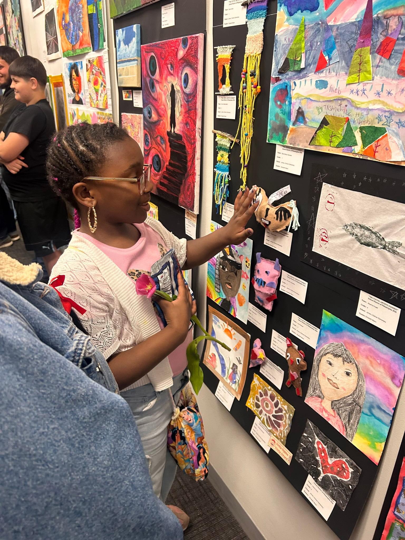 Student standing beside a display of artwork created by James J. Sullivan Elementary School students.